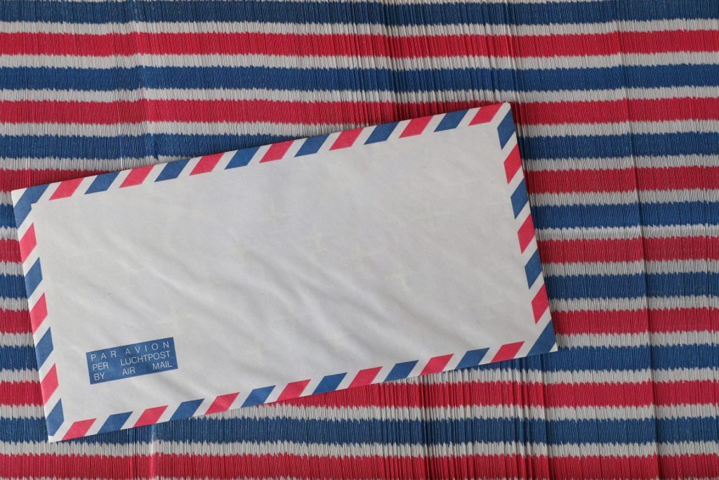 Flat lay of an airmail envelope on a red, white, and blue striped surface.