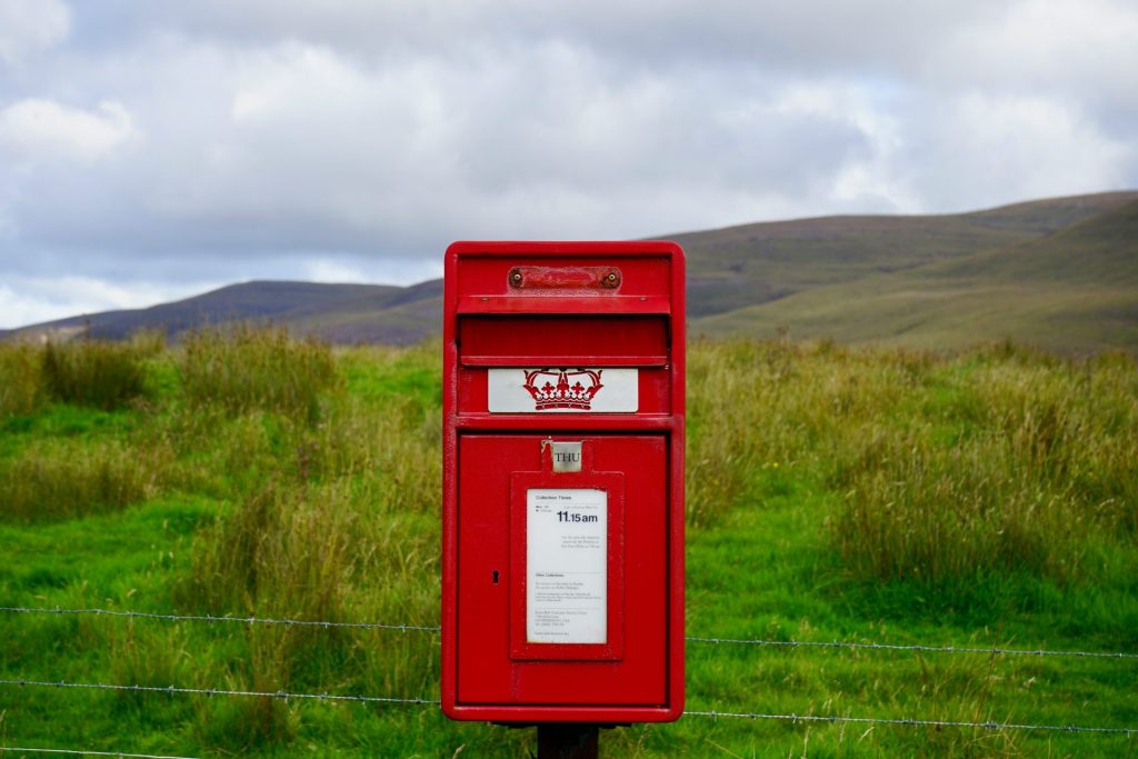 a red mailbox in a grassy field