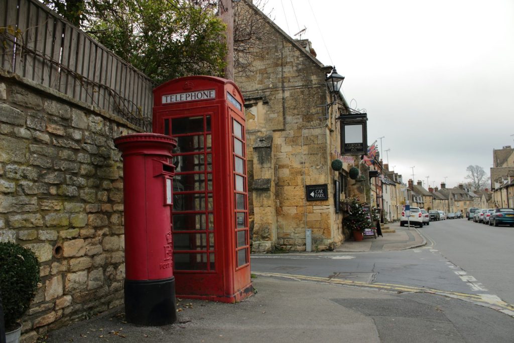 a red telephone booth sitting on the side of a road